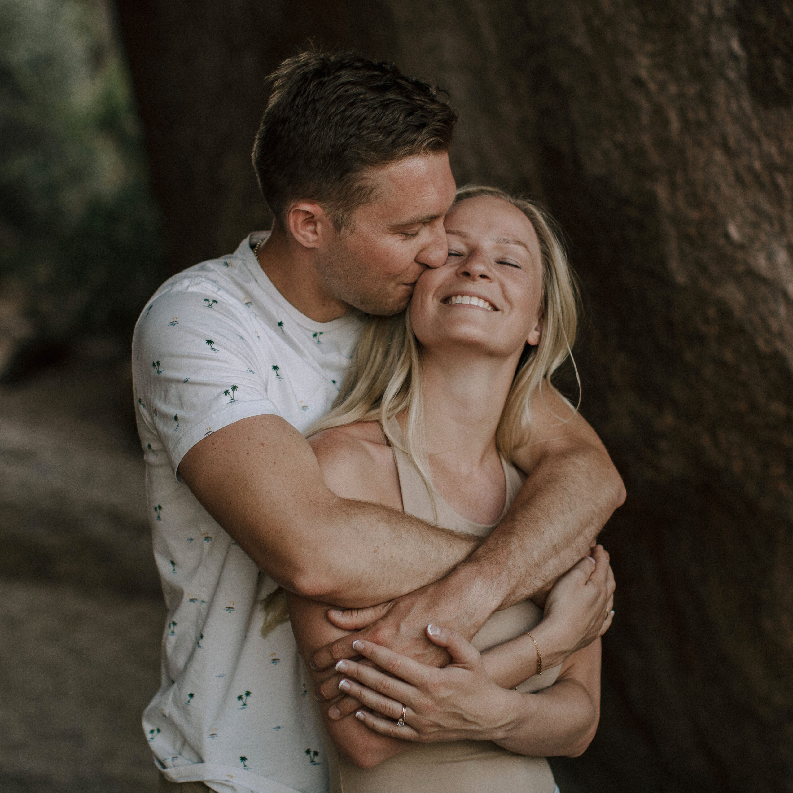 Couple laughing and embracing by desert boulders a natural, candid wedding portrait that feels unposed.
