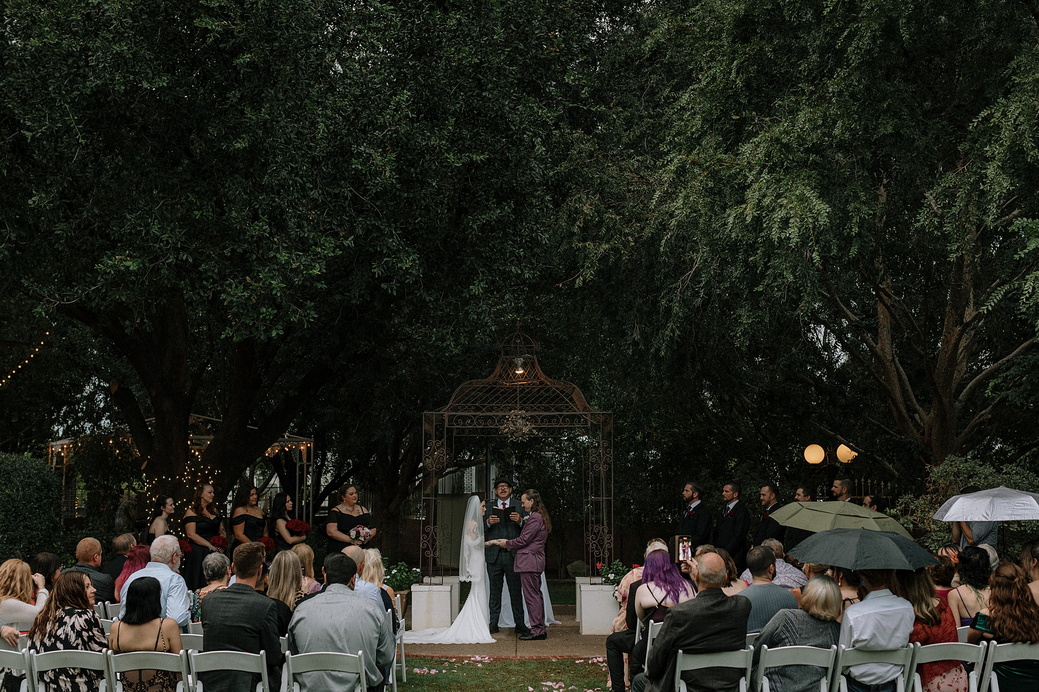 Bride and groom exchanging vows under the trees in light rain