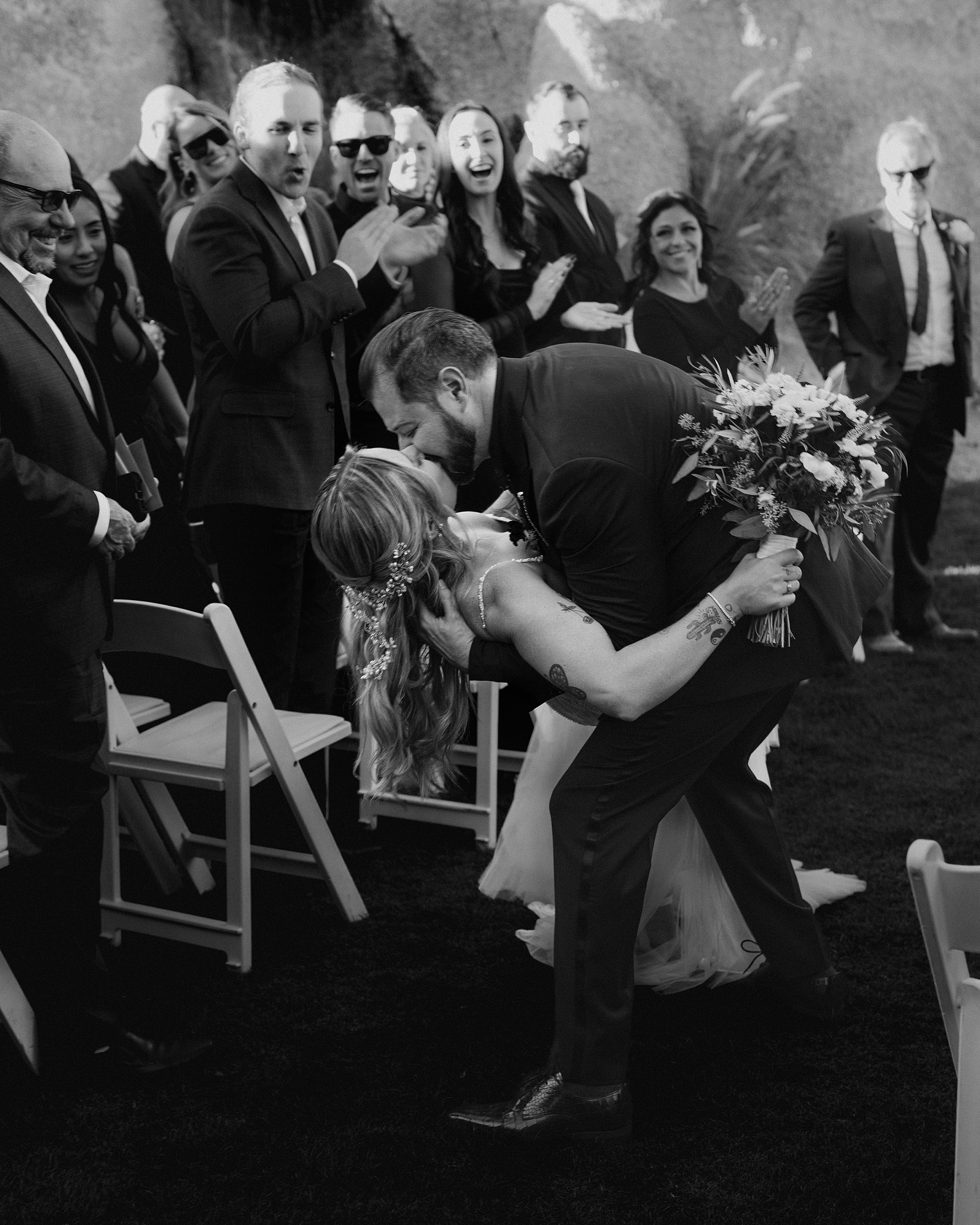 Bride and groom dip and kiss during ceremony exit at The Boulders Resort as guests cheer in the background.