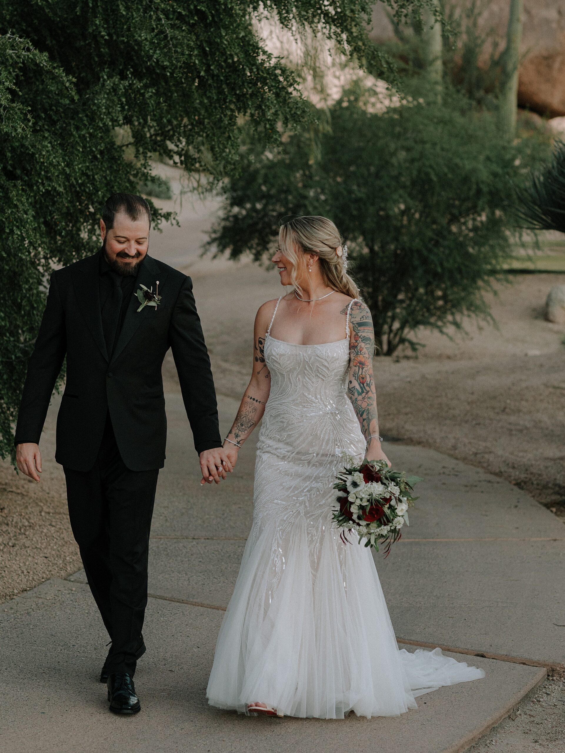Couple holding hands and smiling while walking through the rocks at golden hour