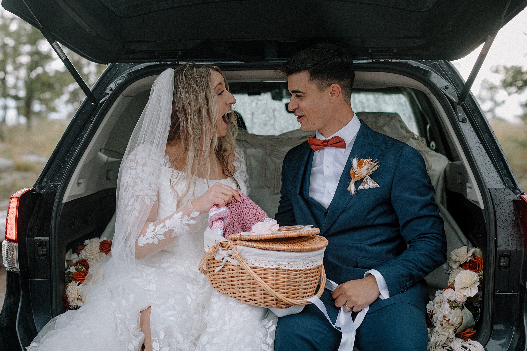 Couple sharing gender reveal after wedding in back of car