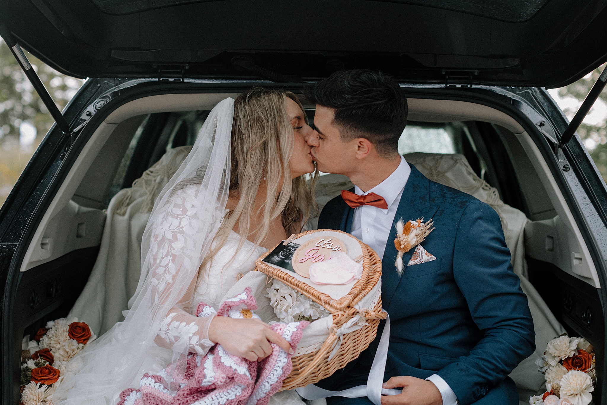 Couple sharing gender reveal after wedding in back of car