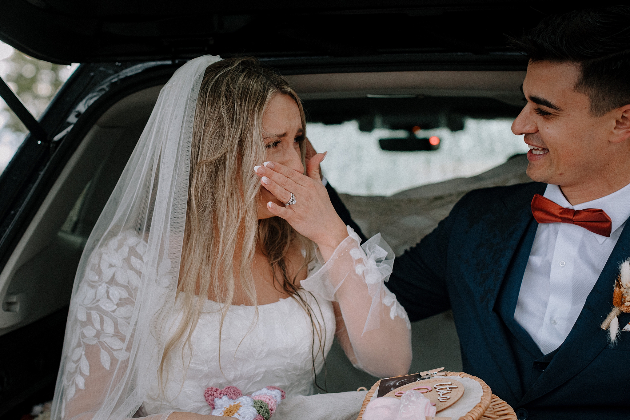 Couple sharing gender reveal after wedding in back of car