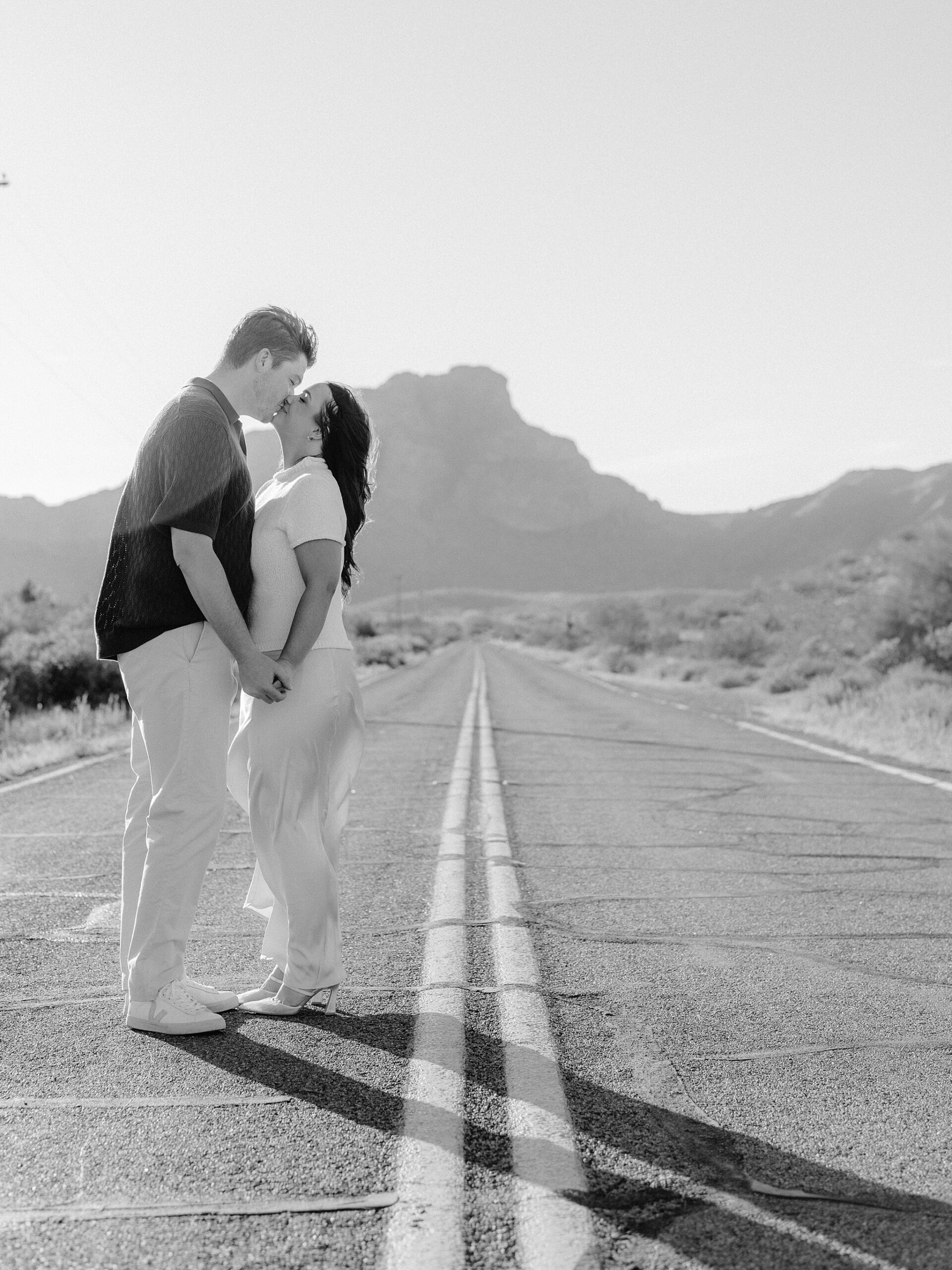 “Couple kissing in the middle of Bush Highway during Arizona desert engagement session”