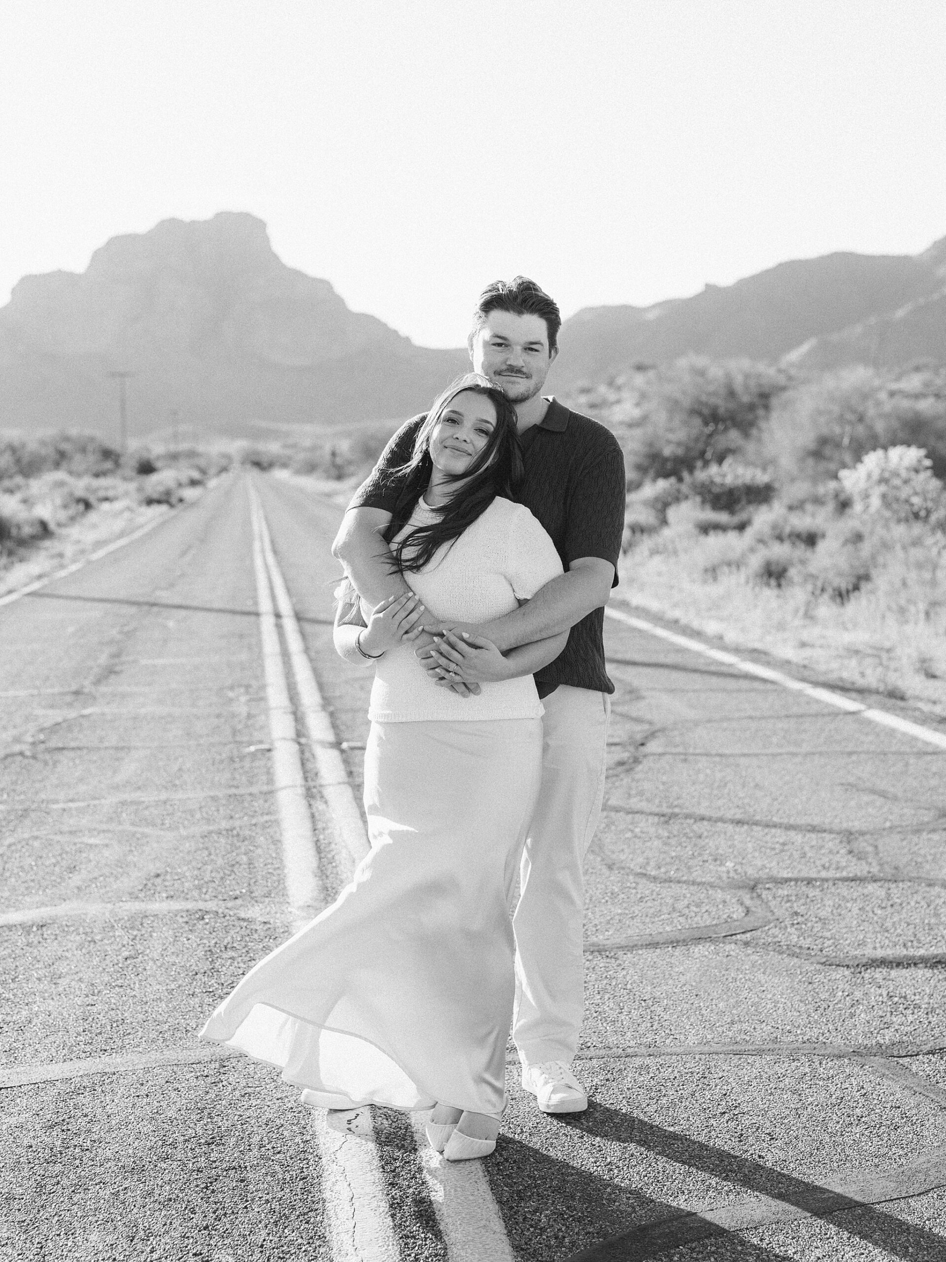 “Couple standing in the middle of Bush Highway during Arizona desert engagement session”