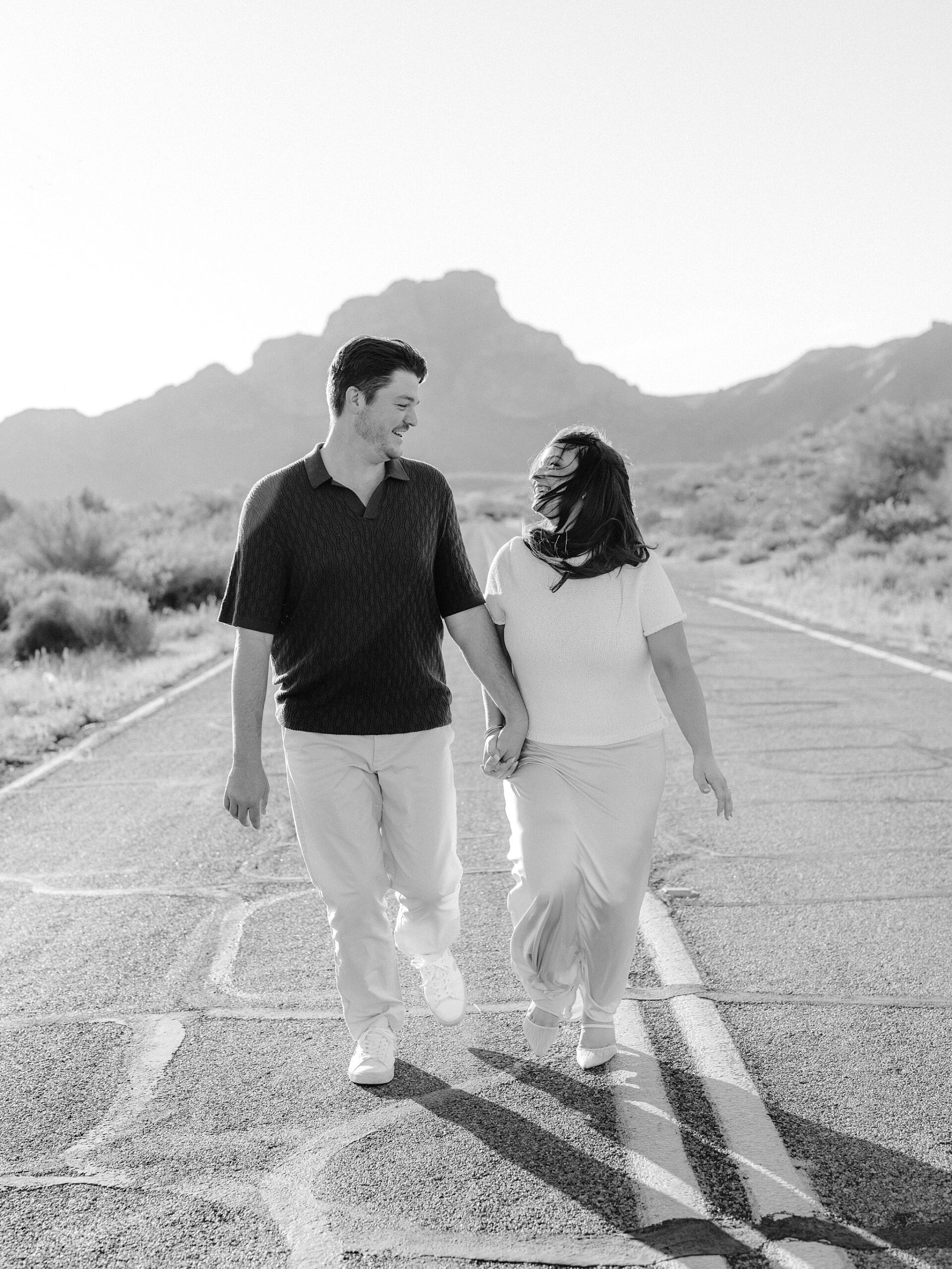 “Couple laughing in the middle of Bush Highway during Arizona desert engagement session”