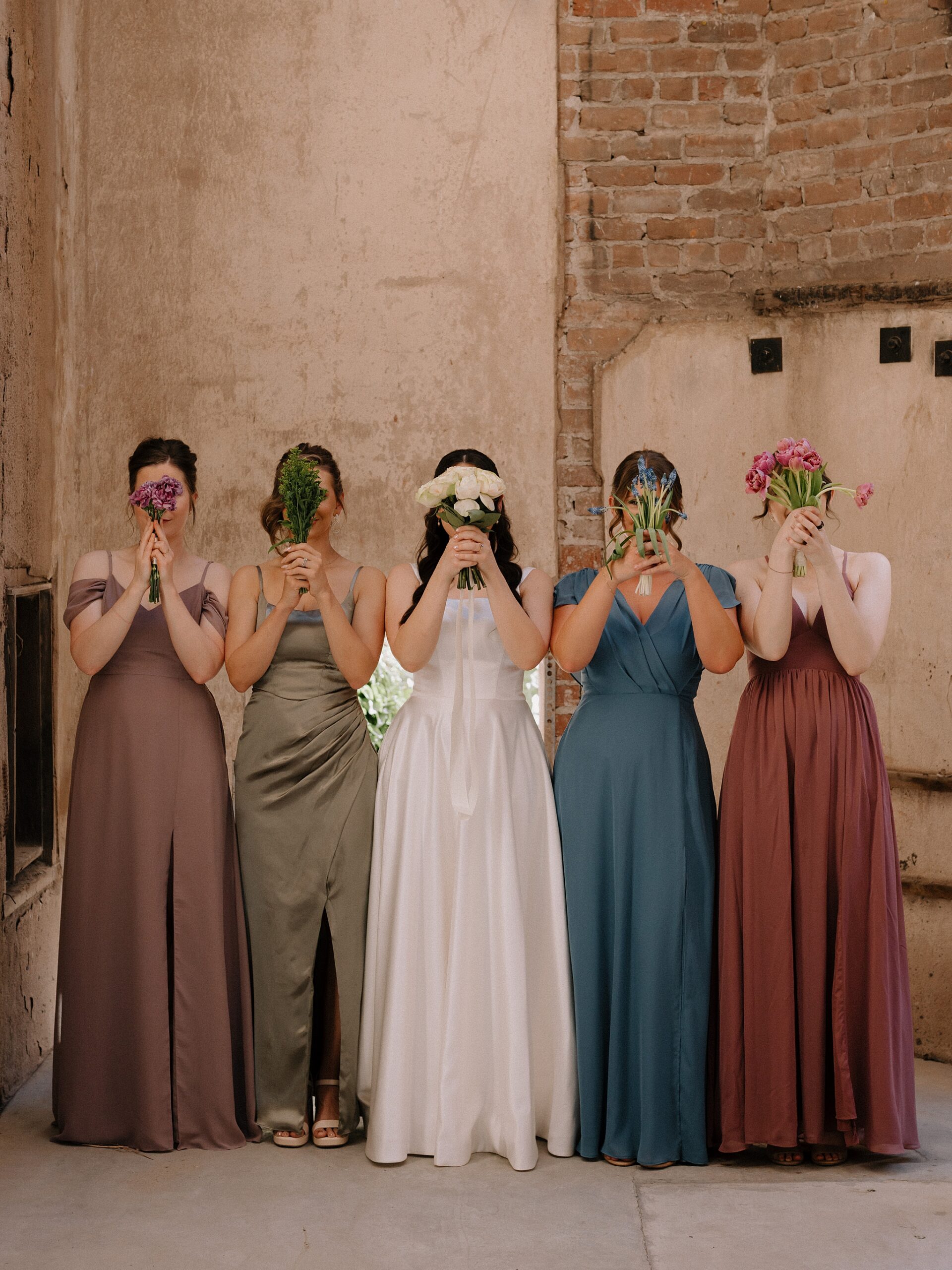 Bride and Bridemaids with flowers in the courtyard at the Monroe street abbey in Phoenix, Arizona