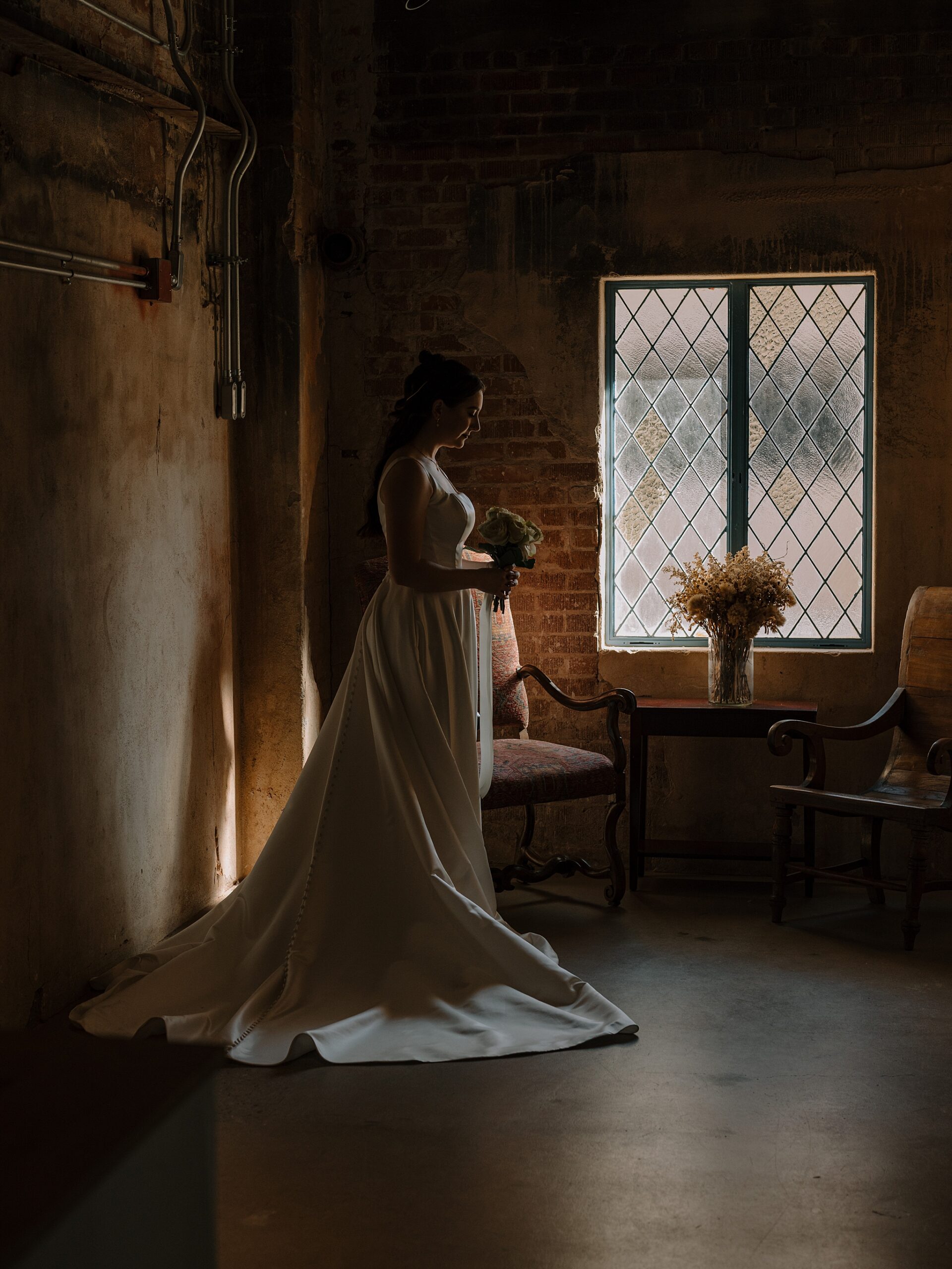 Bride standing in soft window light at the Monroe street abbey in Phoenix, Arizona