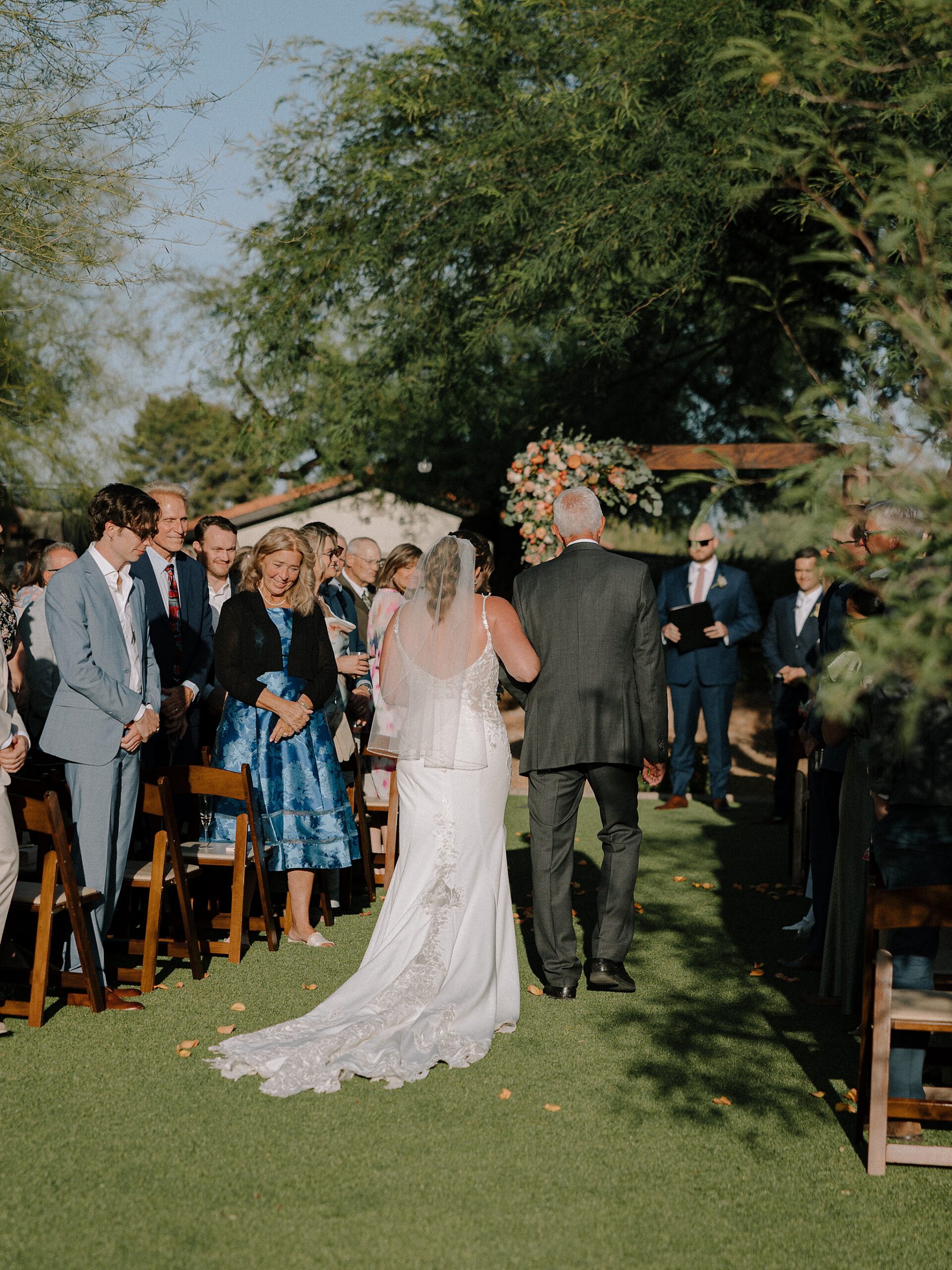 Bride walking down aisle smiling at guests Phoenix backyard wedding
