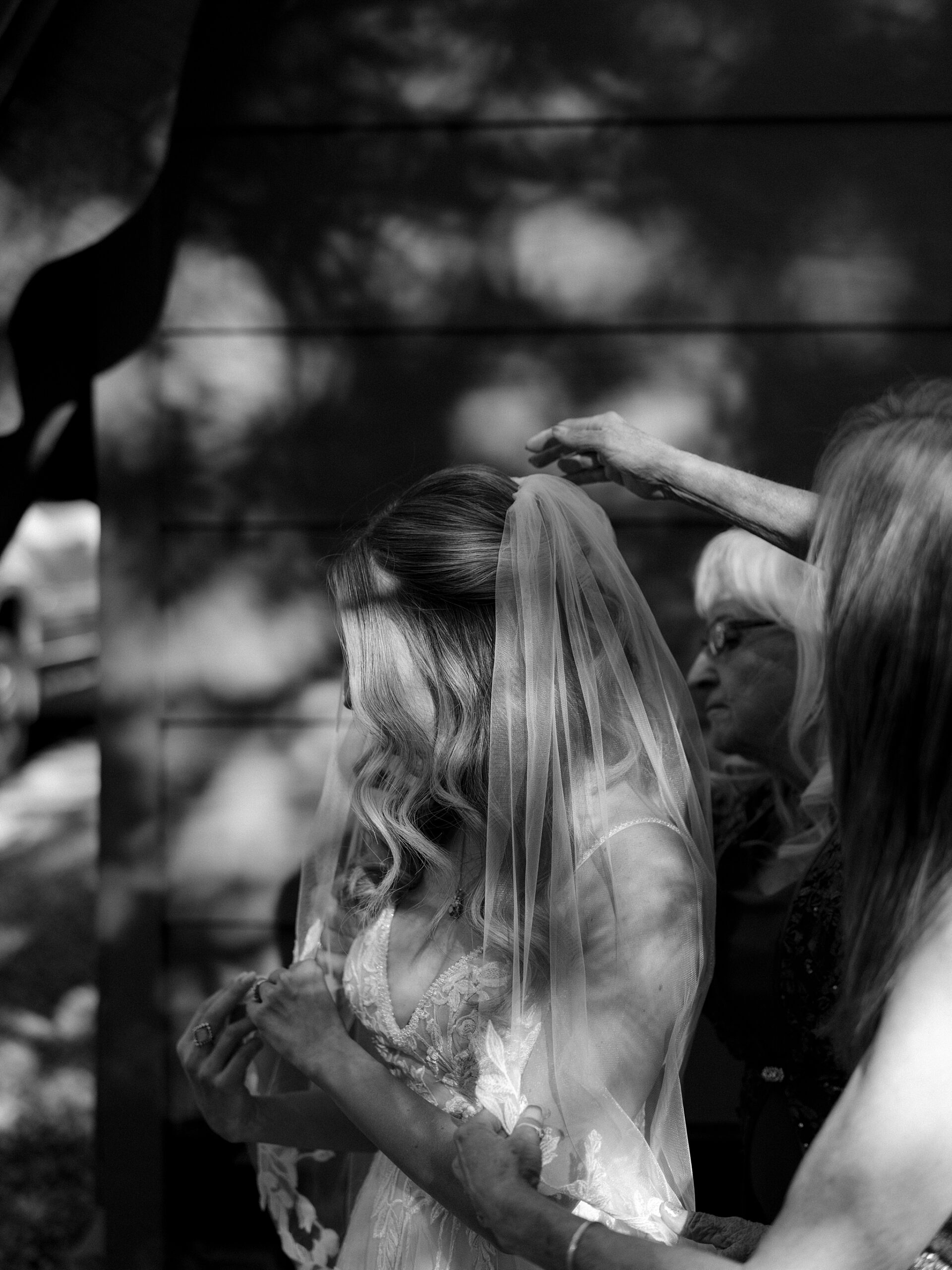 Black and white photo of the bride’s veil being adjusted before her wedding ceremony.