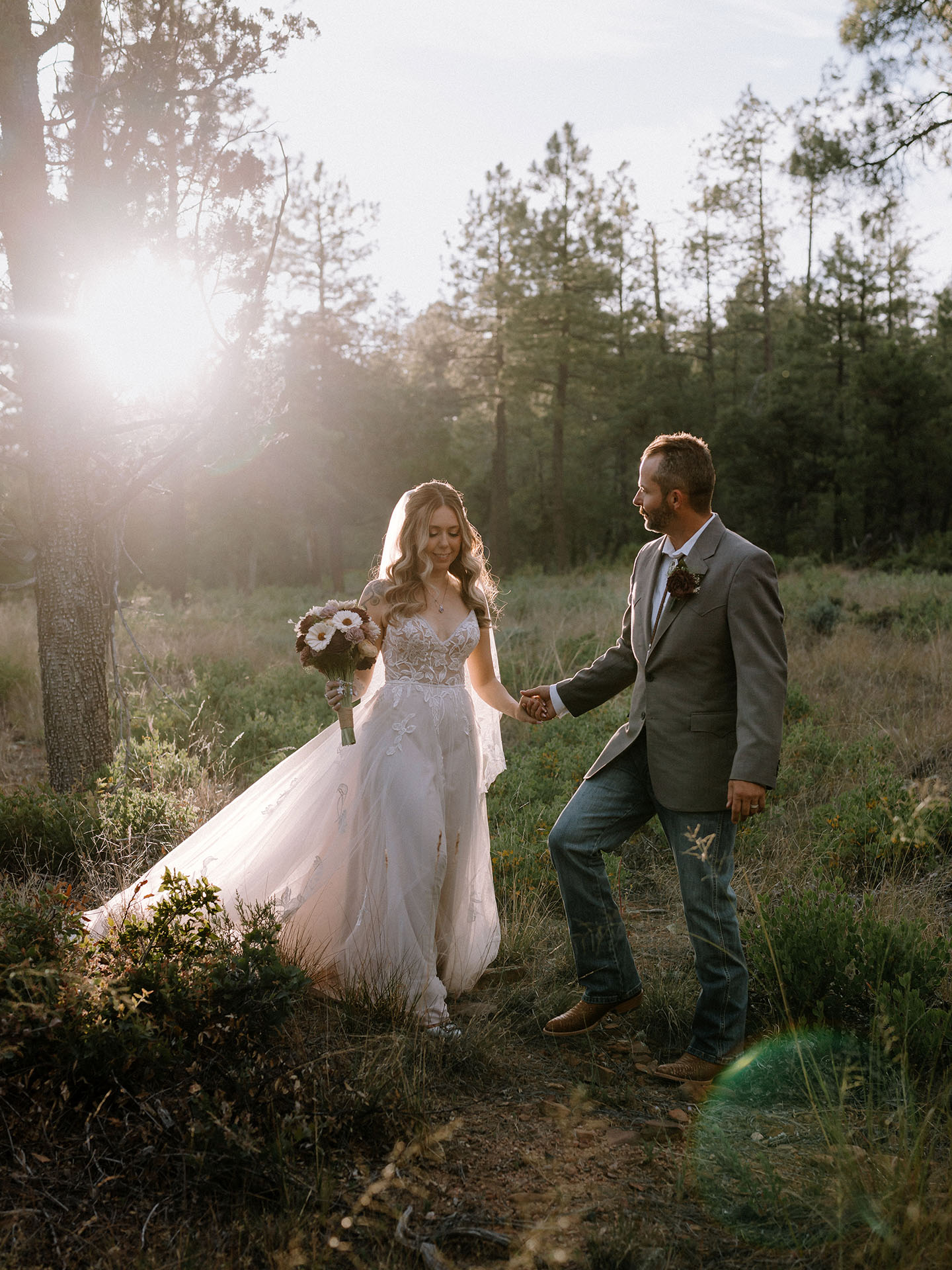 Bride and groom walking through the pines during their Cabins on Strawberry Hill wedding in Strawberry, Arizona.