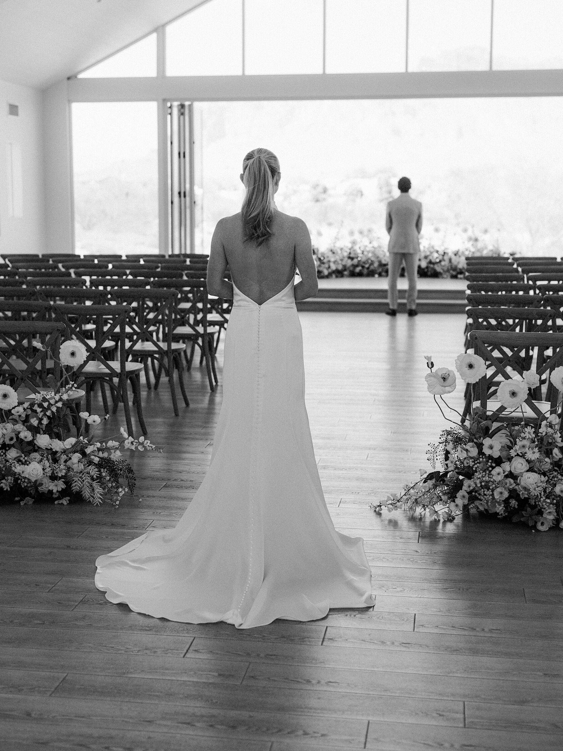 Bride in an open-back wedding dress walking at Desert View Weddings & Events for the first look with the groom