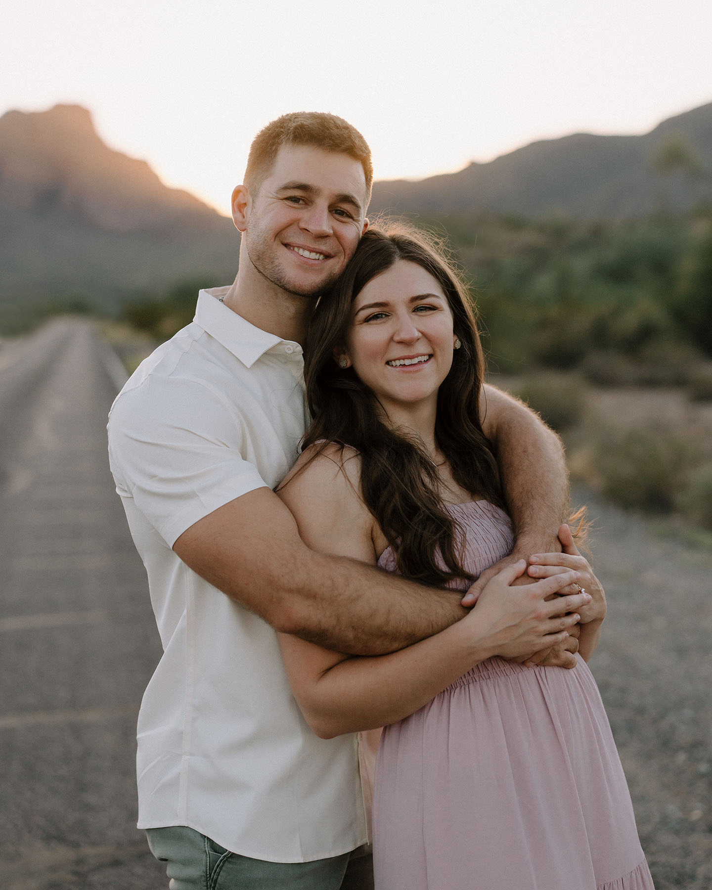 Couple smiling along the salt river with the sun setting in the background